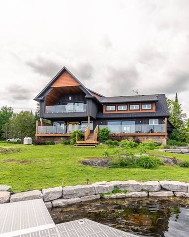Modern two-story house with cream and stone facade, curved glass windows, and metal railings at 80 South Kingsway